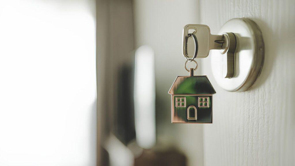 Llaves de una casa insertadas en una puerta que aparece como fondo de la imágen con un poco de blur